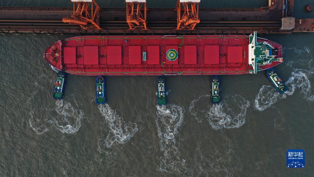 10月20日，一艘轮船在拖轮的协助下向唐山港曹妃甸港区矿石码头靠泊（无人机照片）。