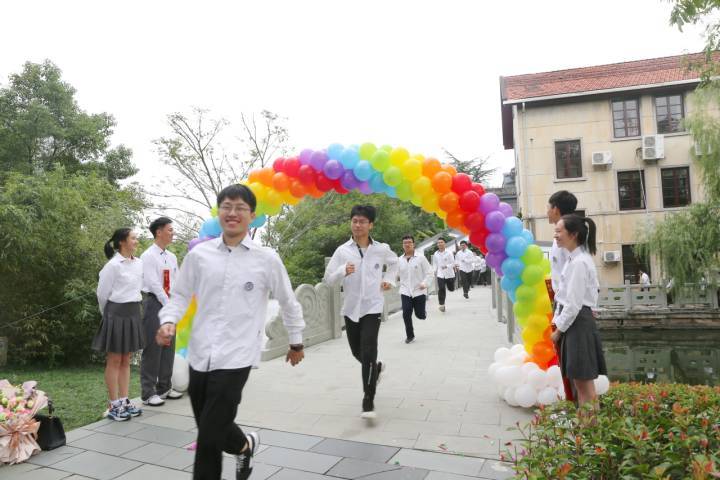 月湖畔,宁波二中的学生们身着统一的白衬衫校服,从竹洲岛后门的桥上