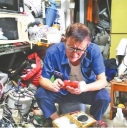 李铭锋在家帮邻里维修家电。