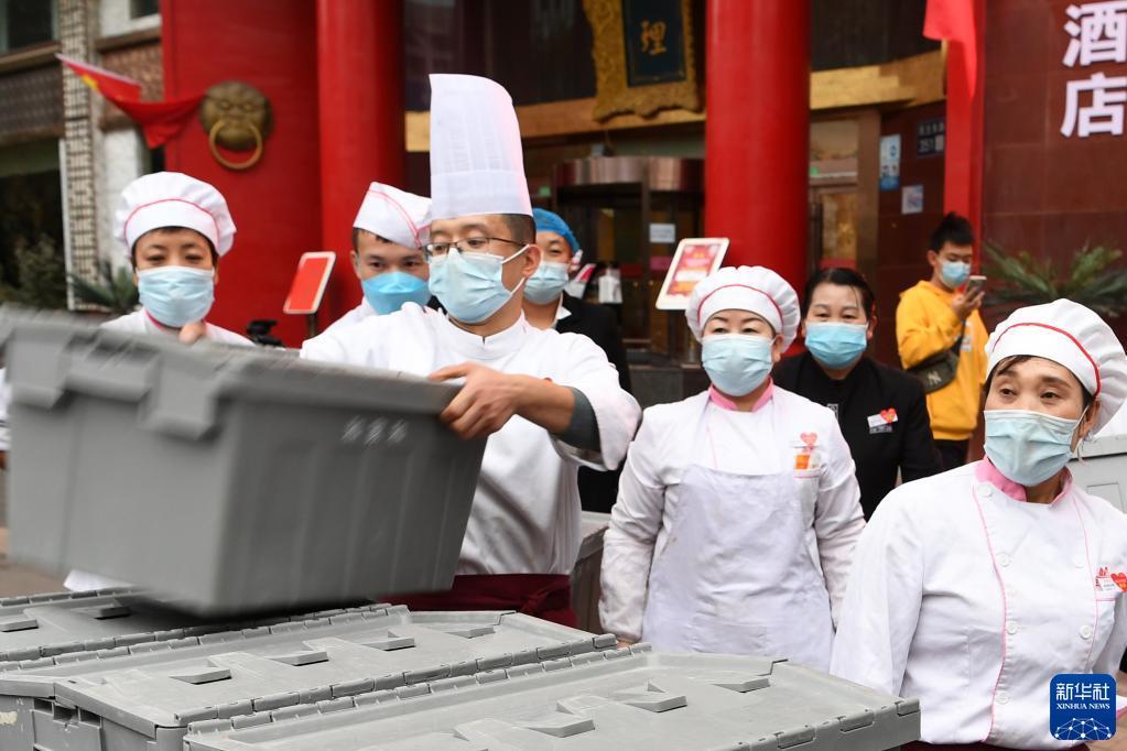 10月25日,在兰州市城关区一餐饮企业,工作人员搬运装有隔离人员餐食的转运箱。新华社记者 范培珅 摄