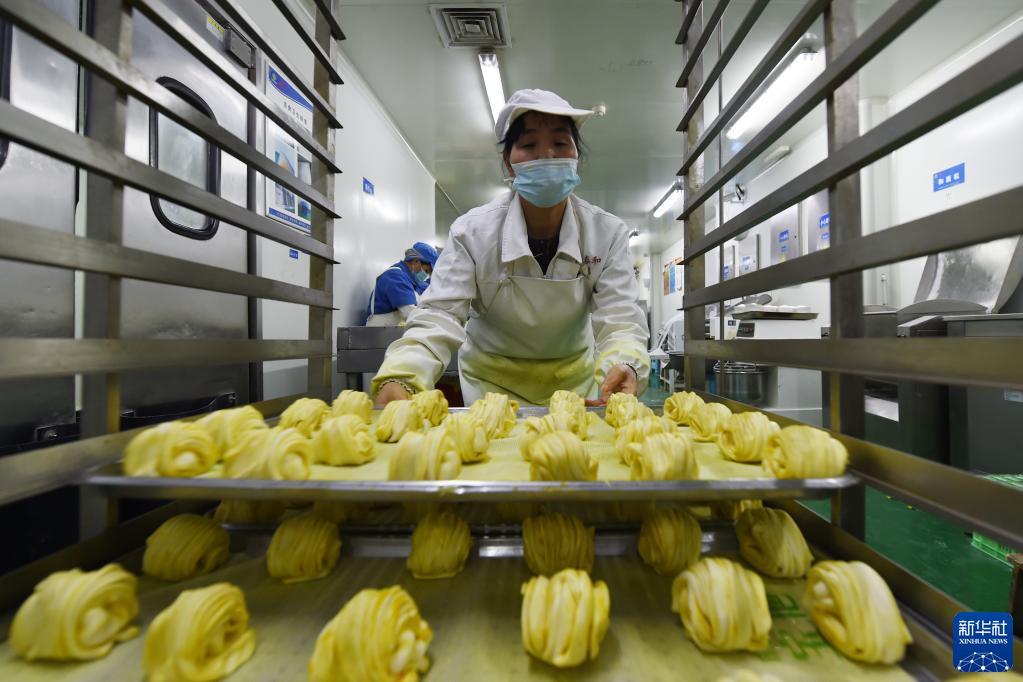 10月26日,在兰州市安宁区一家餐饮集团的中央厨房,工作人员在搬运花卷半成品。新华社记者 范培珅 摄