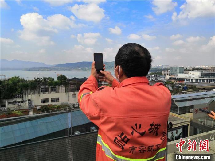 环卫工人在酒店露台赏西湖景。　魏嫣然 摄
