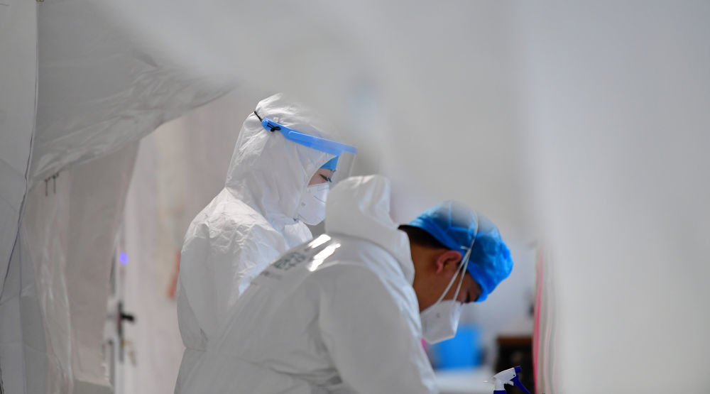 佟锦媚（左）在“猎鹰号”硬气膜实验室的通道做进舱前的防护准备工作（10月26日摄）新华社记者 陈斌 摄