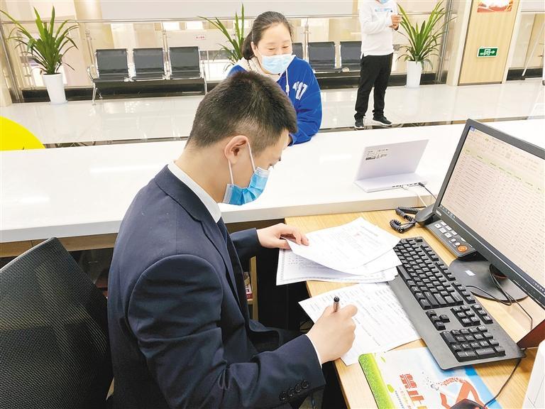 图为工作人员帮群众填写资料,录入信息.