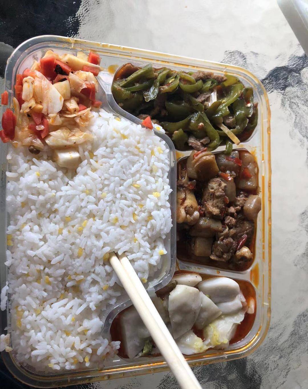 ▲芮先生从社区工作人员那里领到的盒饭。