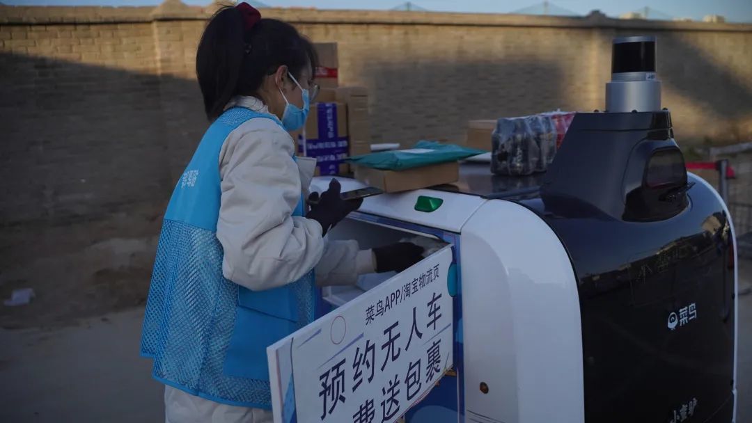 工作人员将包裹装上无人派送车