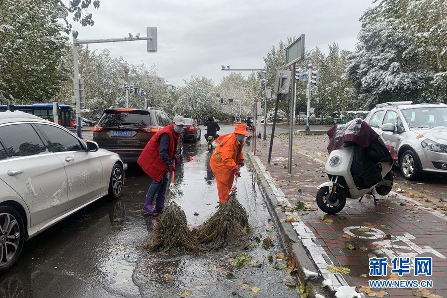 石家庄市志愿者和环卫工人清扫雪水，保障行人安全通行。魏会博摄