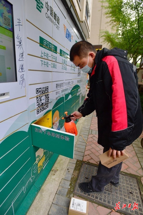 江岸区春兰街跃进家园B区,顺丰派件员对使用的快递柜进行消毒。 记者李永刚 摄