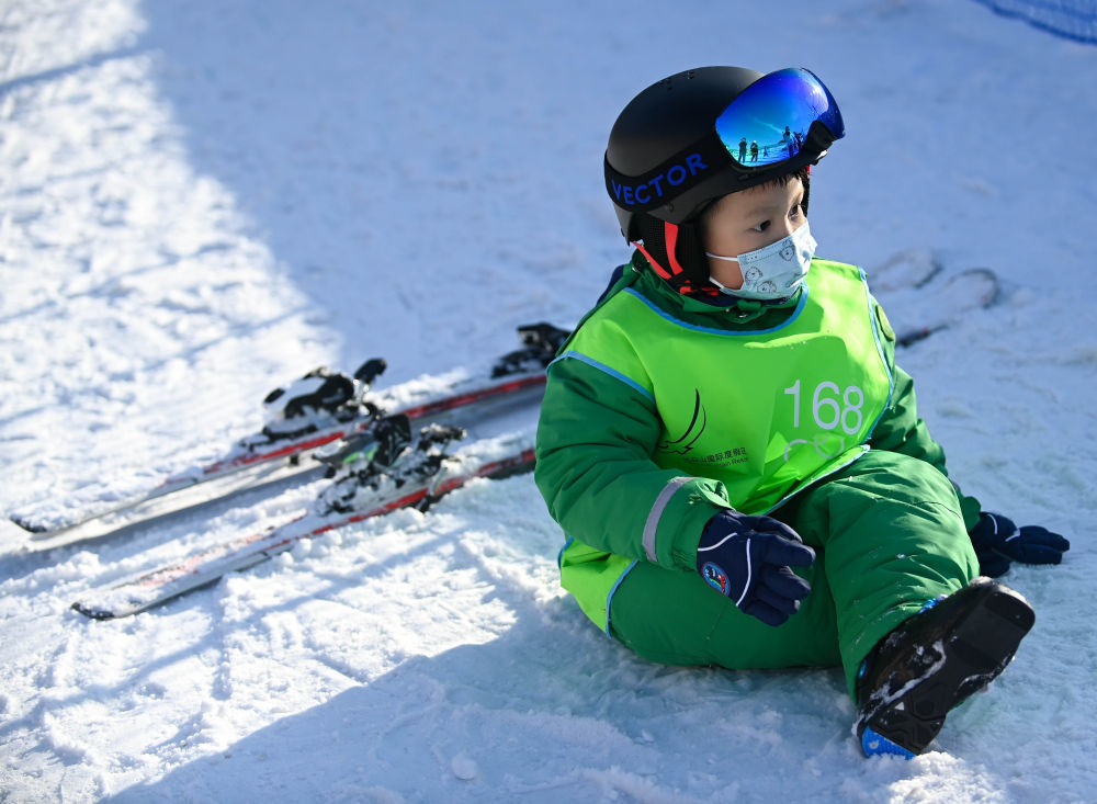 小朋友在长白山国际度假区滑雪场滑雪后坐在地上休息(11月19日摄)
