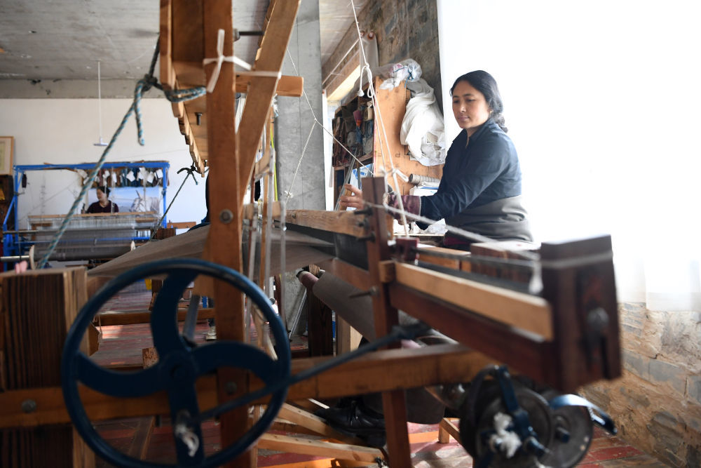 在甘肃省甘南藏族自治州夏河县阿木去乎镇加科村,村民周毛吉在车间使用传统木式纺织机编织手工艺品(9月9日摄)。 新华社记者 陈斌 摄