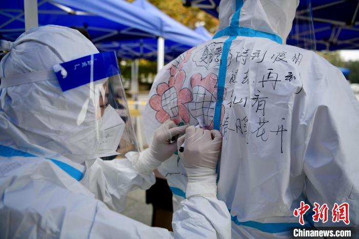 在江西省上饶市铅山县河口镇文化广场，做完核酸检测的医护人员正在防护服上画上各种各样的美图。　丁铭华 摄