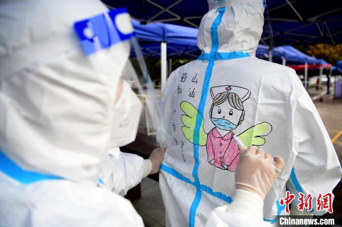 医护人员在防护服上“量身定做”不同的漫画，这让队友们“背”感温暖。　丁铭华 摄