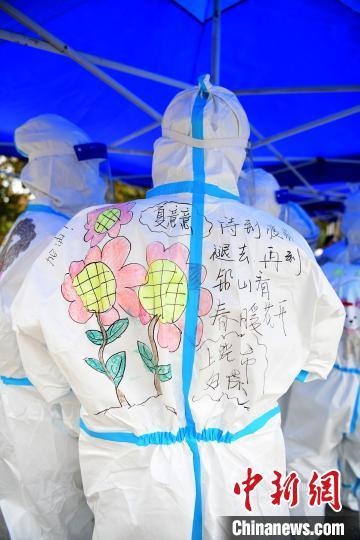 在江西省上饶市铅山县河口镇文化广场，做完核酸检测的医护人员正在防护服上画上各种各样的美图。　丁铭华 摄