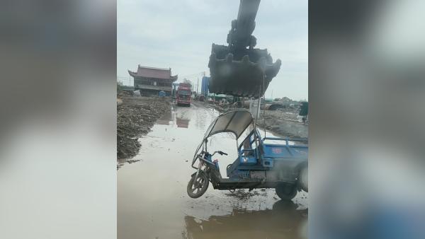 老人将三轮车骑进沟，小伙开挖掘机帮吊起