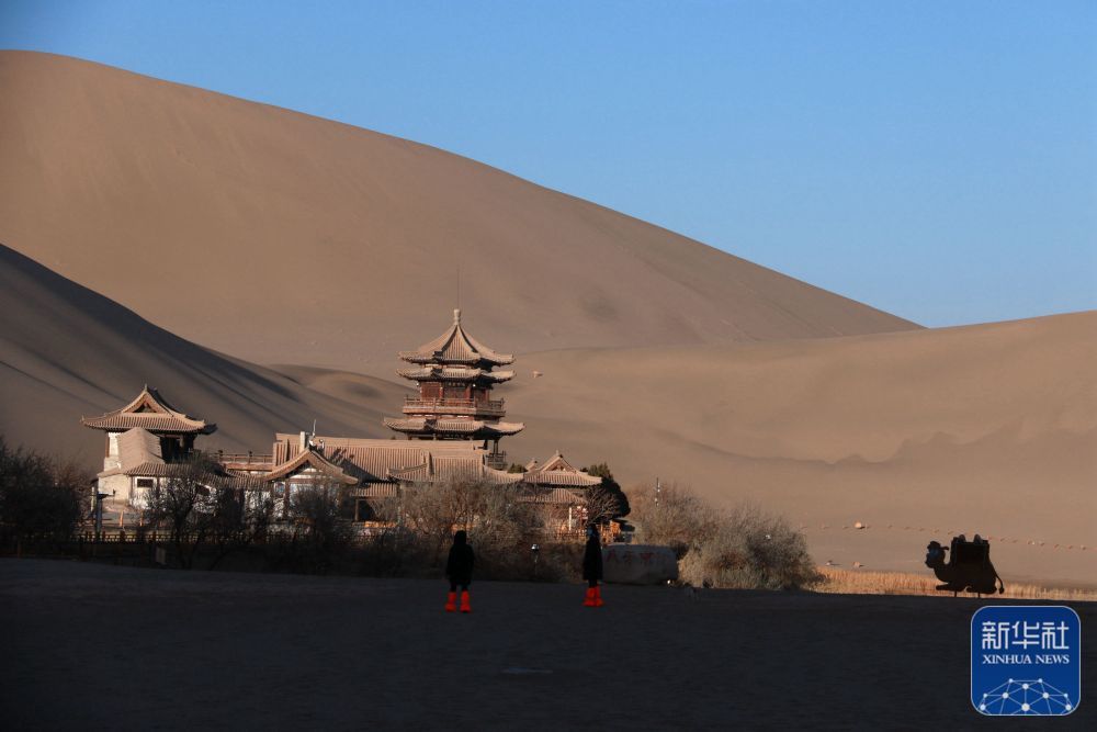 ↑11月27日，游客在甘肃省敦煌市鸣沙山月牙泉景区游览。