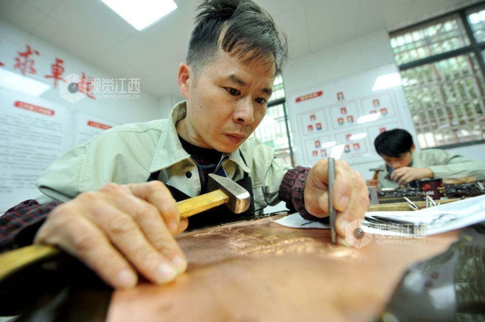 2021年12月17日，江西省贵溪市国家级技能大师、錾铜雕刻“非遗”传承人黄俊军的“弟子”们正在精心创作錾雕作品。