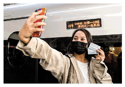 12月10日，乘客准备搭乘深圳北站开往南昌西站的首班列车时，在车厢外自拍留影。新华社记者毛思倩摄
