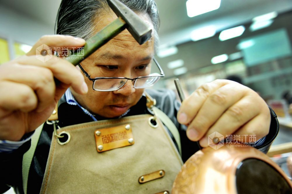 2021年12月17日，江西省贵溪市国家级技能大师、錾铜雕刻“非遗”传承人黄俊军正在精心雕刻工艺铜壶。