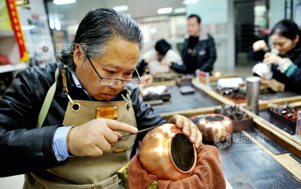 2021年12月17日，江西省贵溪市国家级技能大师、錾铜雕刻“非遗”传承人黄俊军正在精心雕刻工艺铜壶。