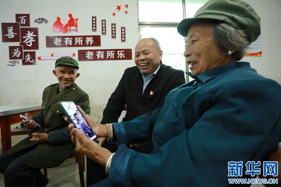 党员黄官星(图中)正在教留守老人用手机与在外务工的子女聊天