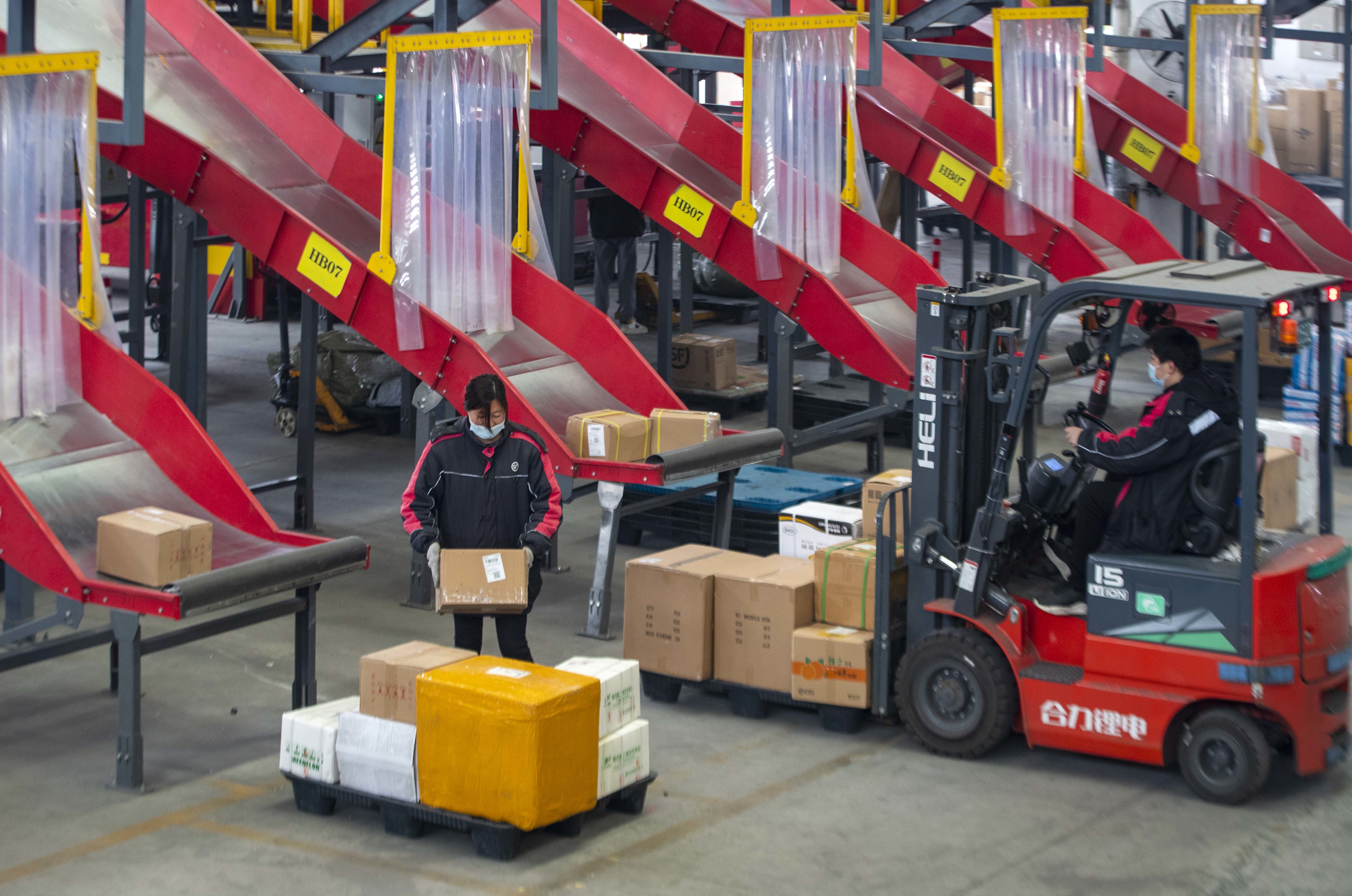 工作人员借助电气化智能分拣设备分拣,打包快递