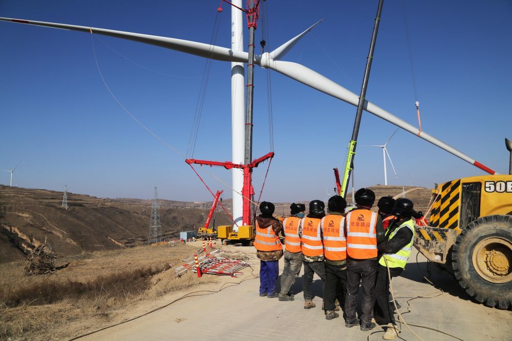 12月24日，工人操作施工机械在甘肃省定西市通渭县境内的风电基地建设现场吊装叶轮。新华社发（王克贤 摄）