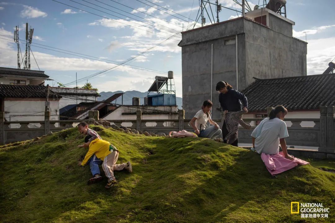 孩子们在村子里玩耍，雨伞村坐落于云南古老的西南丝绸之路上，骡队曾穿过这里，在东南亚和中国之间运货物。Salopek和伙伴们在此路线上徒步，途中杂草丛生，很少有人经过。 摄影：ZHOU NA