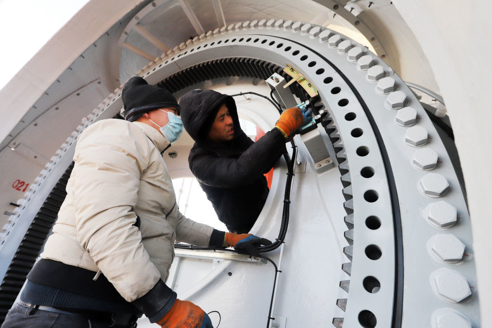 12月24日，工人在甘肃省平凉市崆峒区125兆瓦分散式风电项目施工现场安装设备，该项目将在年底完成设备安装任务。新华社发（吴希会 摄）