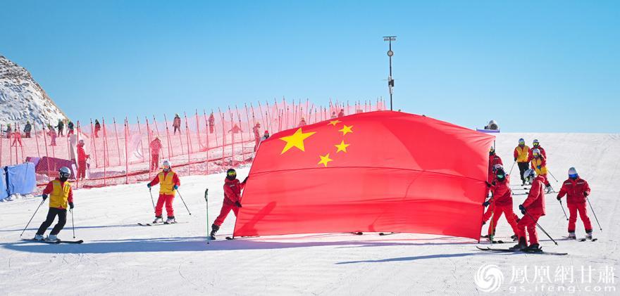 兰州新区滑雪场教练员手托国旗从雪道缓缓滑下,声援冬奥健儿.