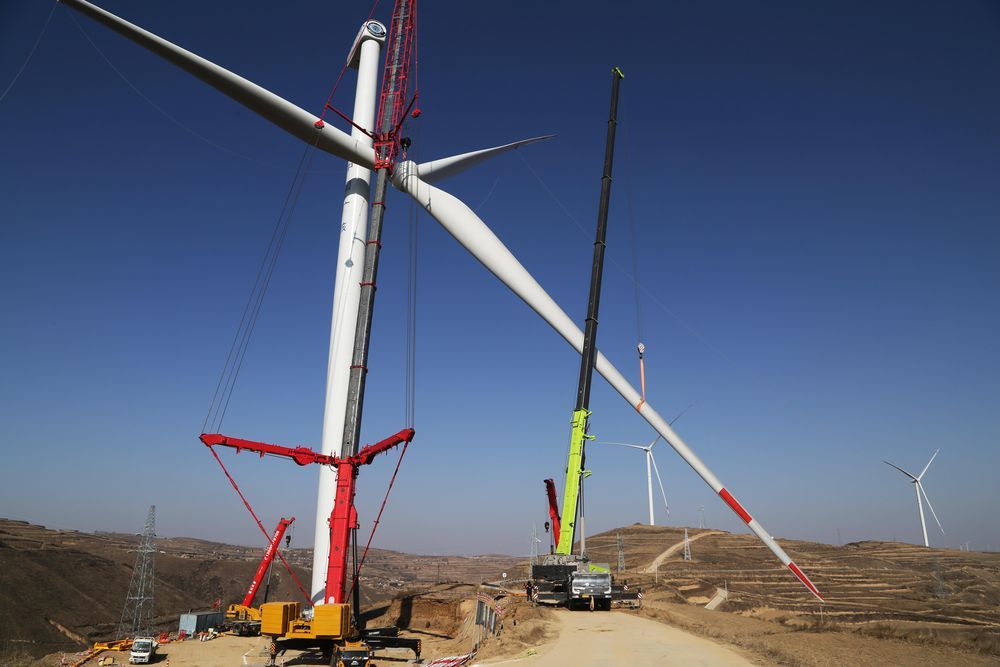 12月24日，施工机械在甘肃省定西市通渭县境内的风电基地建设现场吊装叶轮。
