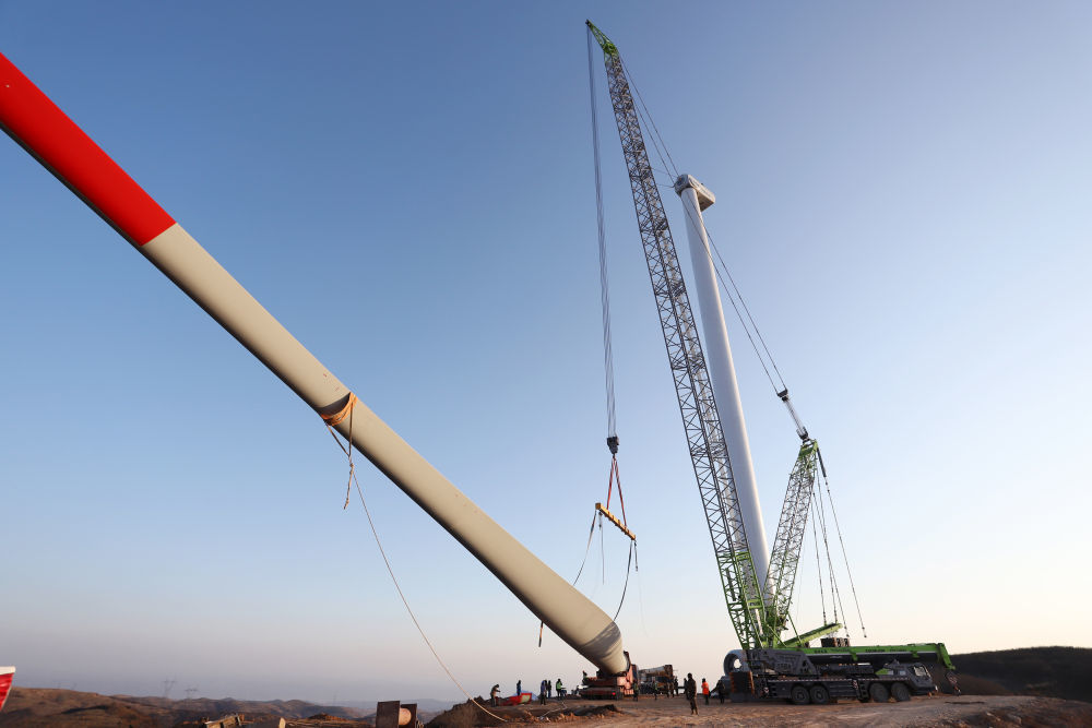 12月24日，工人在甘肃省平凉市崆峒区125兆瓦分散式风电项目施工现场安装设备，该项目将在年底完成设备安装任务。新华社发（吴希会 摄）