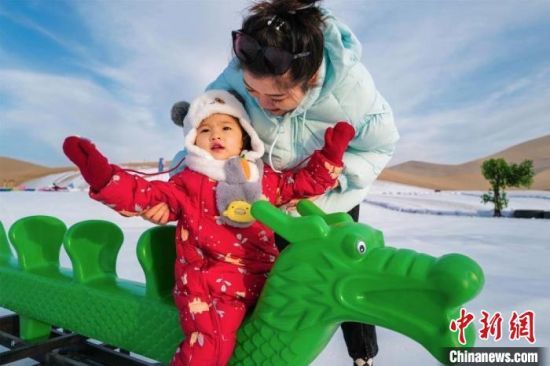 2022年新年伊始，一位家长带孩子到敦煌沙漠露营基地体验沙漠滑雪项目。王斌银　摄