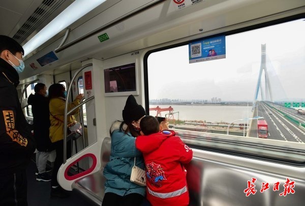 列車從長江邊高架段駛過時,市民紛紛在車窗前觀賞江景.