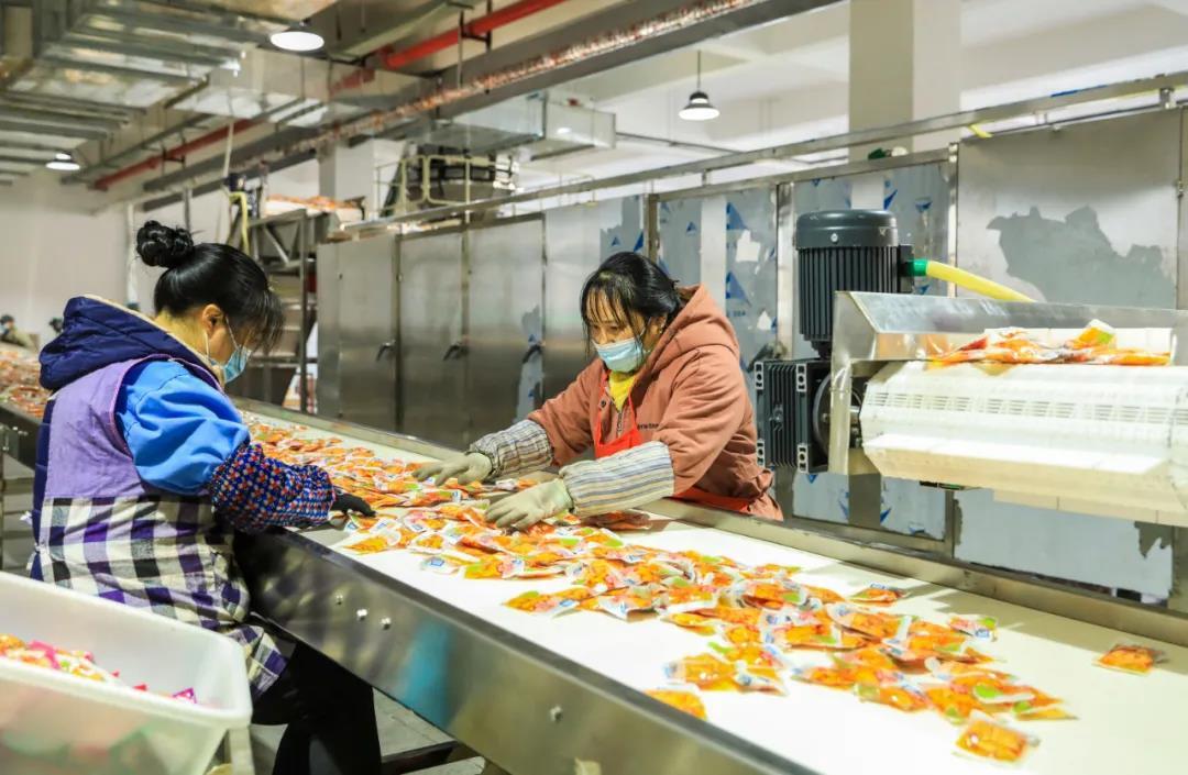 渝美滋休闲食品研发生产项目厂房内,工人在生产线上忙碌.