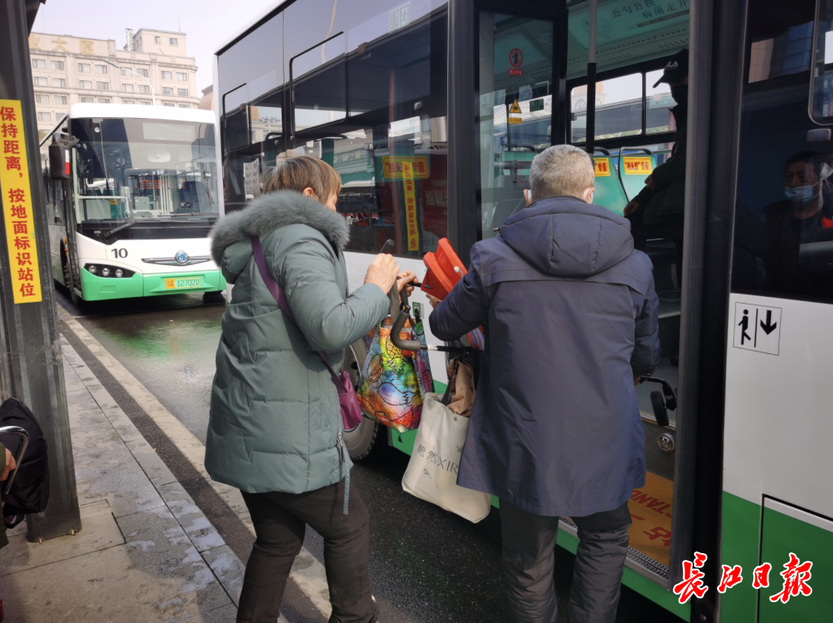 公交汉口火车站站客流平稳,图为公交工作人员在帮乘客将婴儿车抬上车。记者郭佳 摄