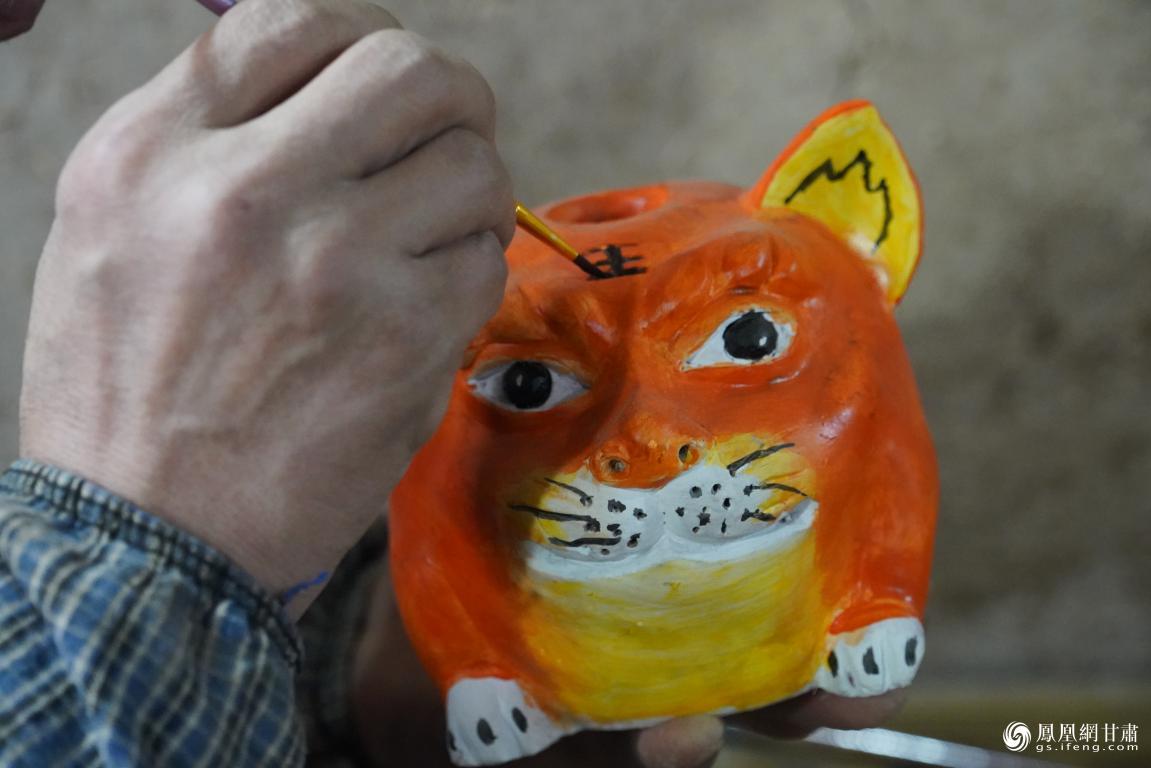 甘肃平凉市民间泥塑艺人刘泉给做成的“拜年虎”进行装饰颜色 郭惠民 摄