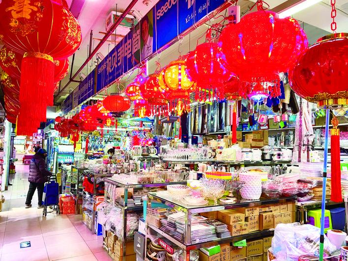 位于繁荣路的繁荣商场，一家日杂摊位挂满了大红灯笼，满满的节日气氛。 赵滨 摄