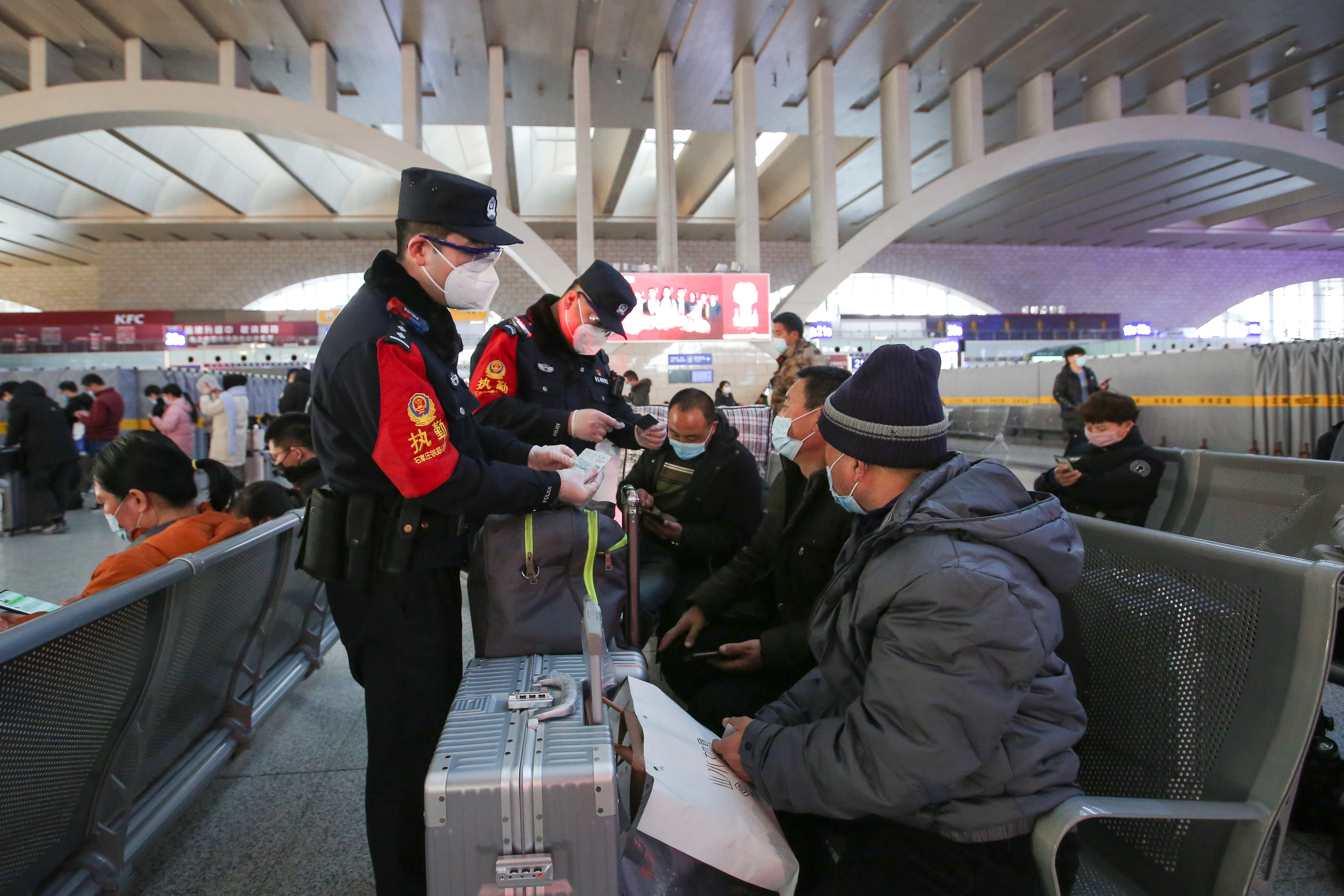 民警刘永瑞与同事在候车室查验旅客身份信息。