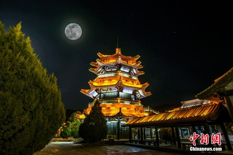 图为敦煌小镇上空的圆月 （多重曝光）中新社发 王斌银 摄