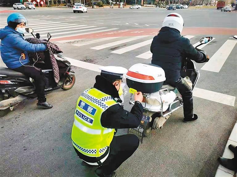 纬二街十字，交警为电动车免费张贴反光车贴。 （记者 张佳 摄）
