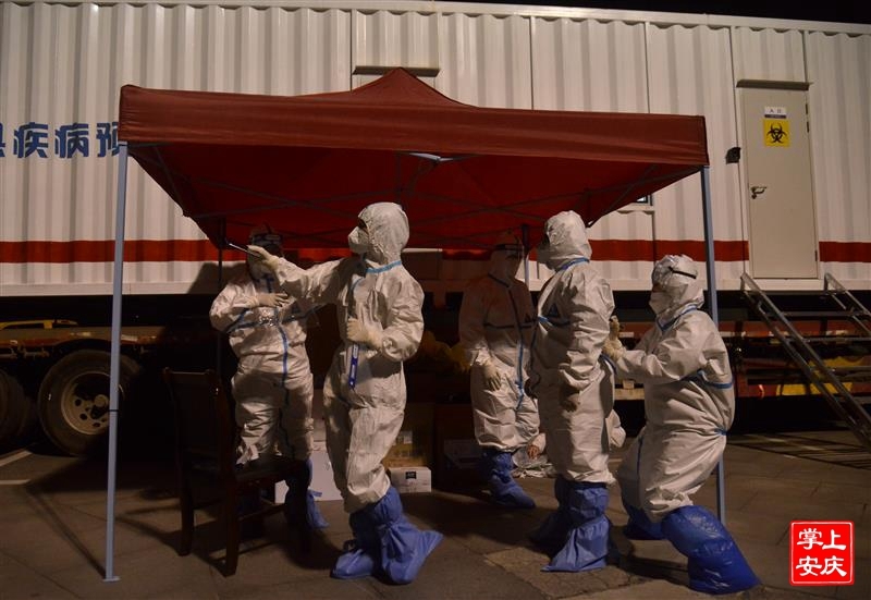 3月9日晚，在迎江区科技广场核酸检测点，来自蚌埠市的医护人员穿戴防疫服准备进仓工作。 王政 摄