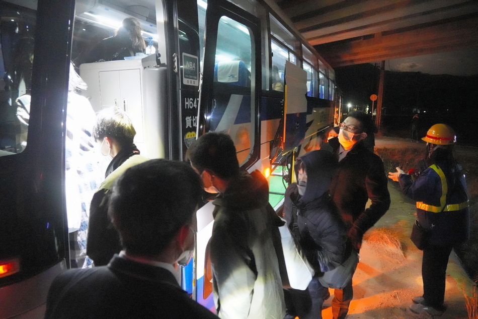 当地时间2022年3月17日凌晨,乘客在工作人员的护送下登上大巴。