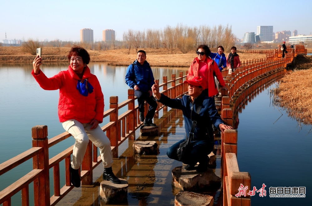 3月10日，游客在张掖国家湿地公园湖泊亲水步道上游览、拍照。