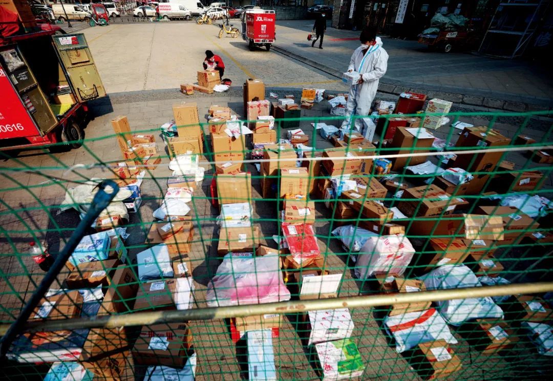 1月19日，陕西西安市，疫情防控下，小区进行封闭管理，快递员在小区的隔离护栏外分拣货物，方便物业工作人员分拣归类。图/人民视觉