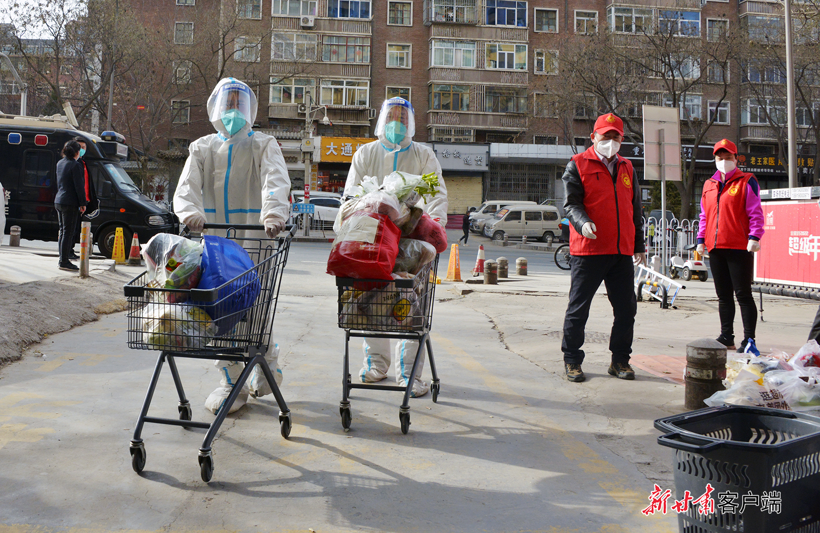 兰州一处疫情防控管控区外，社区志愿者和工作人员正在为居民搬运生活物资。