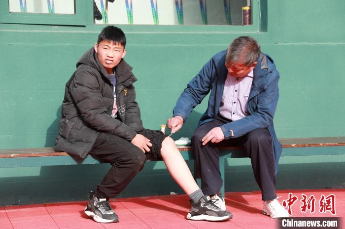 图为教练为裴福鑫的受伤部位擦拭药水。 阚力 摄