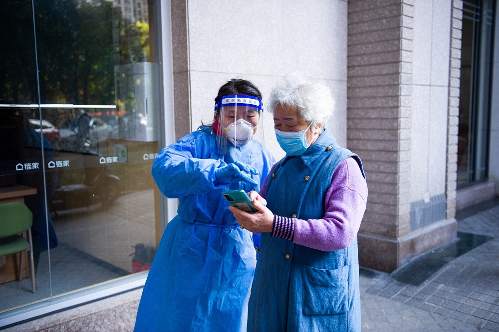 2022年4月4日上午，上海市普陀区宜川街道中远第一居委志愿者帮助老年居民使用智能手机登记“健康云”二维码。