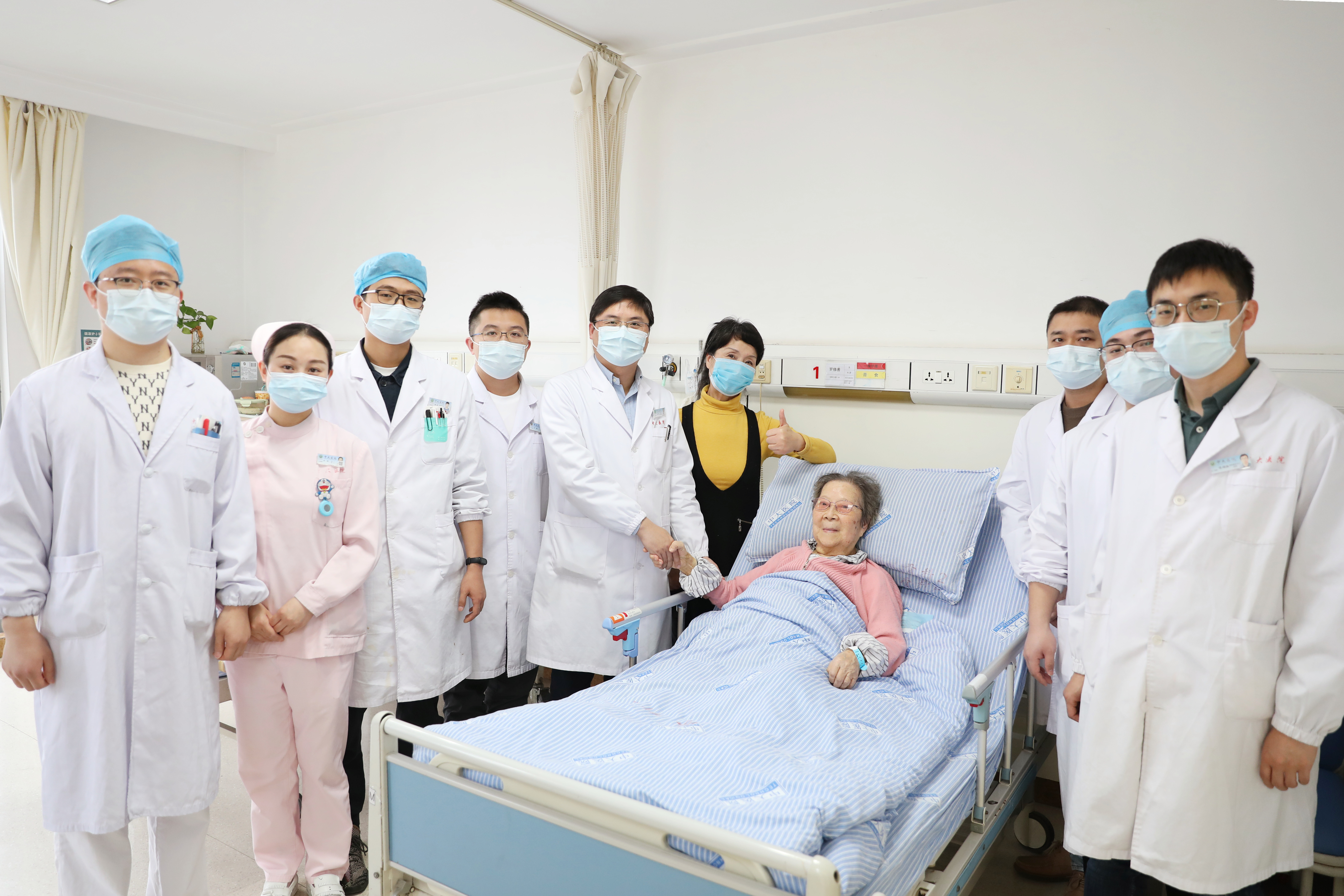 图为：罗奶奶成功术后，芮云峰主任（左五）带领团队查房。王倩摄