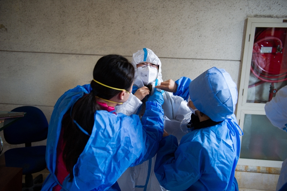 2022年4月4日上午，上海市普陀区宜川街道中远第一居委志愿者正在穿着防护服。  本文图均为 澎湃新闻记者 乐浴峰 图