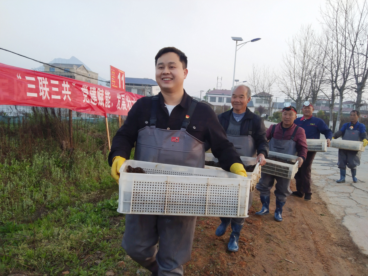 九江银行驻村第一书记朱龙（左一）与村民一起装箱搬运小龙虾。